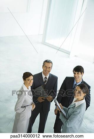 Four businesspeople standing in group, holding files View Large Photo Image Stock Image - Four businesspeople standing in group, holding files. Fotosearch