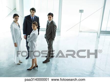 Stock Image - Four executives standing in office building lobby . Fotosearch