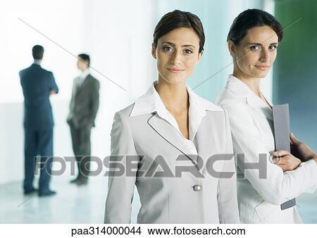 Two businesswomen in lobby, one holding file View Large Photo Image Picture - Two businesswomen in lobby, one holding file. Fotosearch