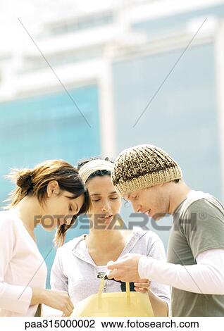 Stock Image - Three young friends looking at purchase. Fotosearch