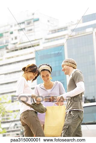 Three young friends with shopping bags standing together View Large Photo Image Stock Image - Three young friends with shopping bags standing together. Fotosearch