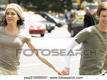 Young couple holding hands in busy street View Large Photo Image Stock Image - Young couple holding hands in busy street. Fotosearch