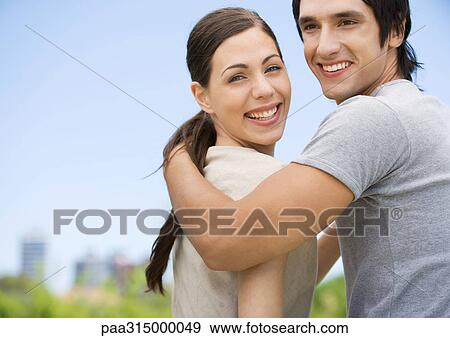 Young couple looking over shoulders, smiling View Large Photo Image Stock Photo - Young couple looking over shoulders, smiling. Fotosearch
