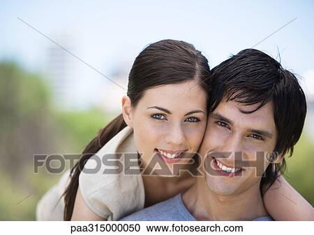 Stock Image - Young couple smiling, cheek to cheek. Fotosearch