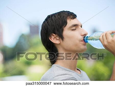Young man drinking water from bottle View Large Photo Image Stock Photo - Young man drinking water from bottle. Fotosearch
