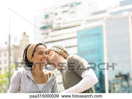 Stock Photo - Young man kissing girlfriend on cheek. Fotosearch