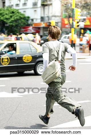 Stock Photo - Young man running across street. Fotosearch