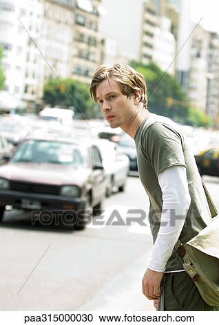 Young man standing next to busy street View Large Photo Image Stock Image - Young man standing next to busy street. Fotosearch
