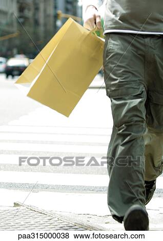 Young man walking with shopping bag View Large Photo Image Stock Photo - Young man walking with shopping bag. Fotosearch