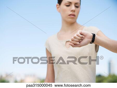 Stock Photography - Young woman checking watch. Fotosearch
