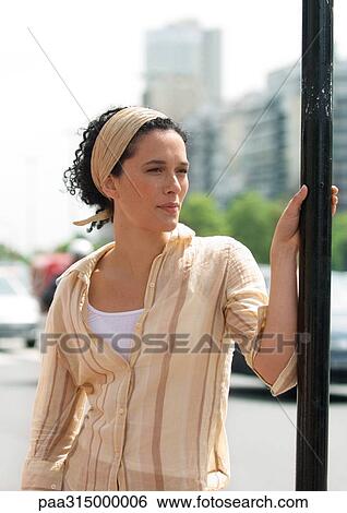 Young woman holding onto sign post View Large Photo Image Stock Photograph - Young woman holding onto sign post. Fotosearch