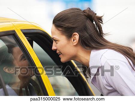 Young woman leaning toward taxi, speaking View Large Photo Image Stock Photography - Young woman leaning toward taxi, speaking. Fotosearch
