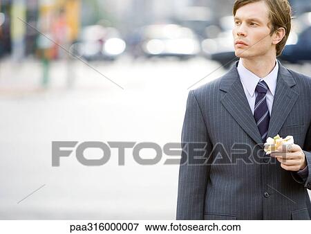Businessman eating on the go View Large Photo Image Stock Photo - Businessman eating on the go. Fotosearch