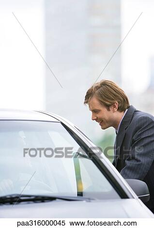 Businessman next to car, speaking to driver View Large Photo Image Stock Photography - Businessman next to car, speaking to driver. Fotosearch