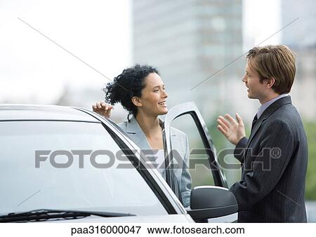 Businessman speaking to woman as she gets into car View Large Photo Image Stock Photo - Businessman speaking to woman as she gets into car. Fotosearch