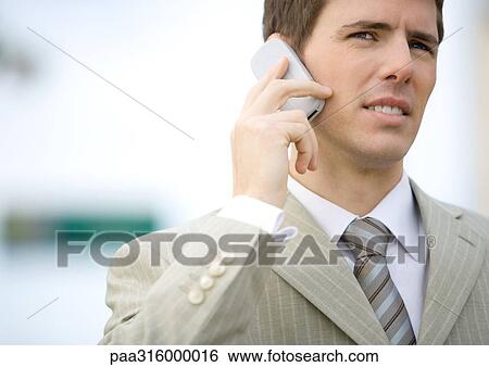 Businessman using cell phone, squinting View Large Photo Image Stock Photograph - Businessman using cell phone, squinting. Fotosearch