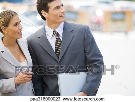 Businesswoman and man standing close together, looking up View Large Photo Image Stock Image - Businesswoman and man standing close together, looking up. Fotosearch