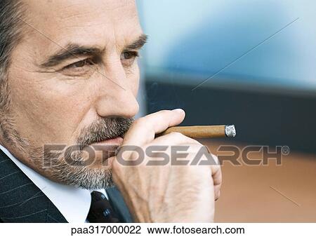 Stock Image - Businessman smoking cigar. Fotosearch