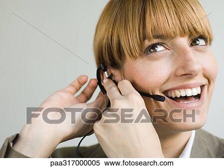 Woman smiling and putting on headset View Large Photo Image Stock Photography - Woman smiling and putting on headset. Fotosearch