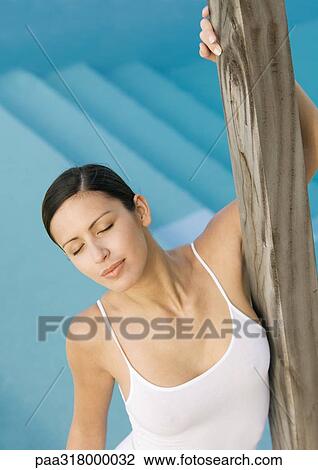 Woman leaning against wooden pole near pool View Large Photo Image Stock Image - Woman leaning against wooden pole near pool . Fotosearch