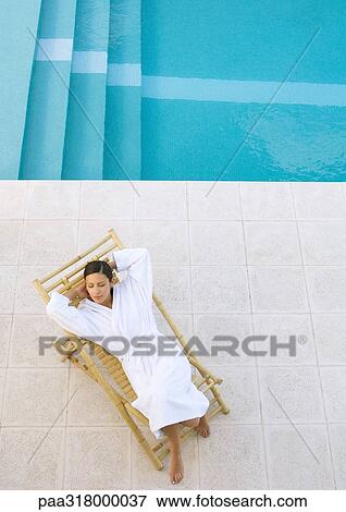 Woman lounging in chair by pool, high angle view View Large Photo Image Stock Photo - Woman lounging in chair by pool, high angle view. Fotosearch