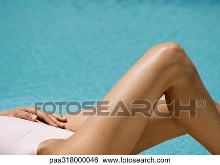 Woman lying by side of pool, partial view View Large Photo Image Stock Photograph - Woman lying by side of pool, partial view. Fotosearch
