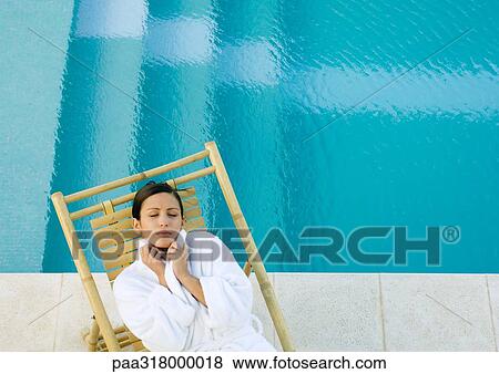 Woman lying in lounge chair at edge of pool, wearing bathrobe View Large Photo Image Stock Photo - Woman lying in lounge chair at edge of pool, wearing bathrobe. Fotosearch