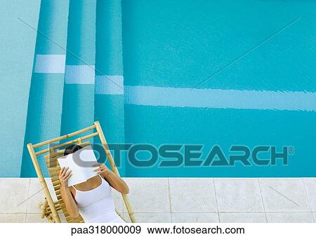 Woman sitting in lounge chair by pool, reading, high angle view View Large Photo Image Stock Photo - Woman sitting in lounge chair by pool, reading, high angle view. Fotosearch