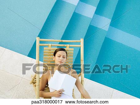 Woman sleeping in lounge chair at edge of pool with book on chest View Large Photo Image Stock Photo - Woman sleeping in lounge chair at edge of pool with book on chest. Fotosearch
