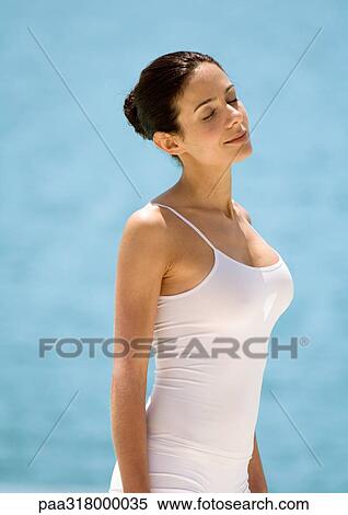 Woman standing in sun with eyes closed, water in background View Large Photo Image Stock Photography - Woman standing in sun with eyes closed, water in background. Fotosearch