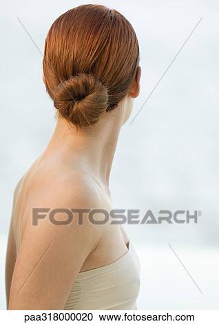 Stock Image - Woman with red hair in bun and strapless top, rear view. Fotosearch