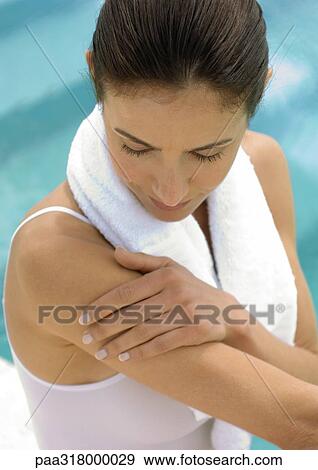 Woman with towel around neck looking at arm View Large Photo Image Stock Photo - Woman with towel around neck looking at arm. Fotosearch