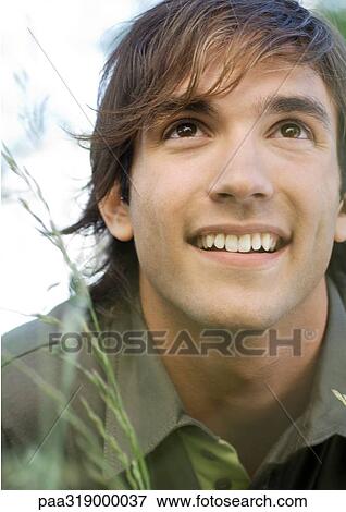 Young man in grass smiling, portrait View Large Photo Image Stock Photo - Young man in grass smiling, portrait. Fotosearch
