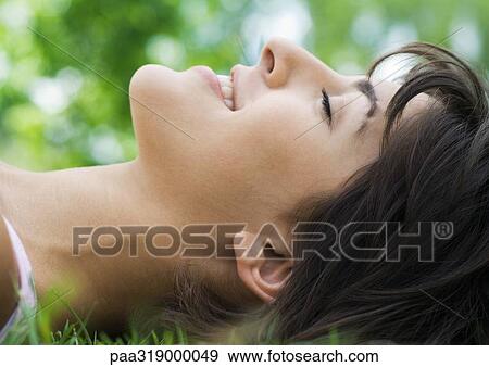 Young woman lying in grass with eyes closed View Large Photo Image Stock Photo - Young woman lying in grass with eyes closed. Fotosearch