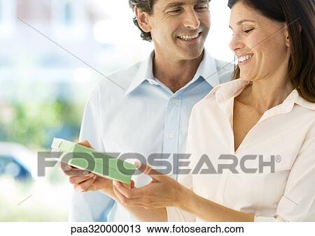 Stock Image - Mature couple, man handing woman gift. Fotosearch