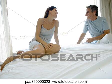 Mature couple sitting on bed, smiling at each other View Large Photo Image Stock Image - Mature couple sitting on bed, smiling at each other. Fotosearch