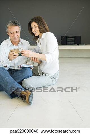 Stock Photograph - Mature couple sitting on floor looking at cds. Fotosearch
