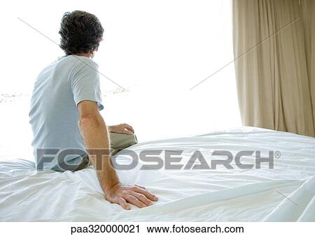 Mature man sitting alone on bed, looking out window View Large Photo Image Stock Image - Mature man sitting alone on bed, looking out window. Fotosearch