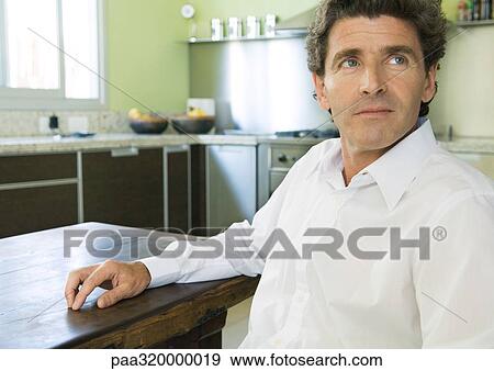 Mature man sitting in kitchen View Large Photo Image Stock Photo - Mature man sitting in kitchen. Fotosearch