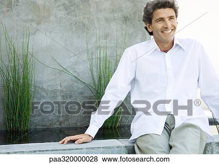 Mid-adult man sitting in front of home View Large Photo Image Stock Photo - Mid-adult man sitting in front of home. Fotosearch