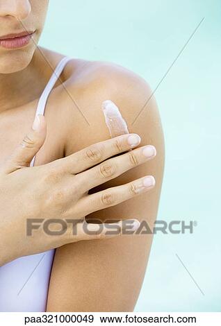 Stock Photo - Woman applying cream to shoulder. Fotosearch