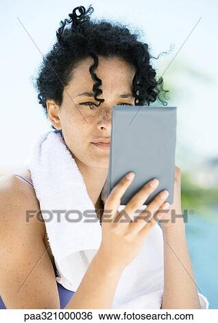 Stock Photograph - Woman looking in hand mirror. Fotosearch