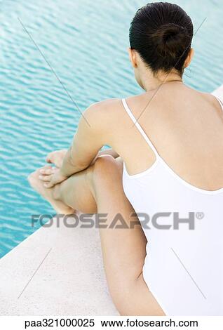 Stock Photography - Woman sitting by edge of pool. Fotosearch