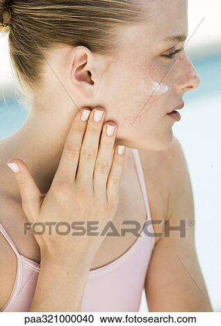 Young woman applying moisturizer to face View Large Photo Image Stock Image - Young woman applying moisturizer to face. Fotosearch
