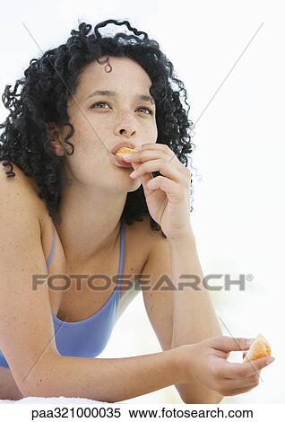 Stock Photography - Young woman eating orange. Fotosearch