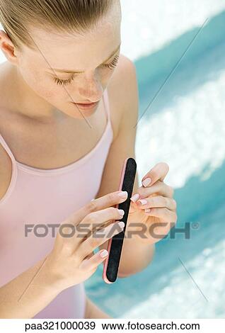 Stock Photo - Young woman filing nails. Fotosearch