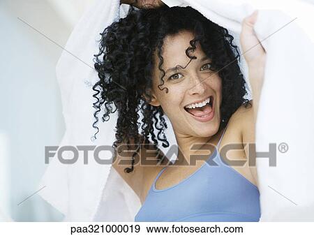 Young woman holding towel over head and making face View Large Photo Image Stock Photo - Young woman holding towel over head and making face. Fotosearch