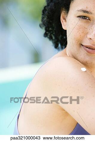 Stock Image - Young woman with dab of sunscreen on shoulder. Fotosearch