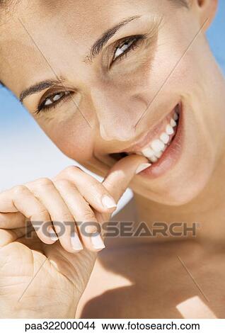 Woman biting thumb, close-up View Large Photo Image Picture - Woman biting thumb, close-up. Fotosearch