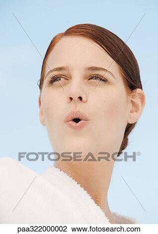 Stock Image - Woman wearing bathrobe and puckering lips, portrait. Fotosearch